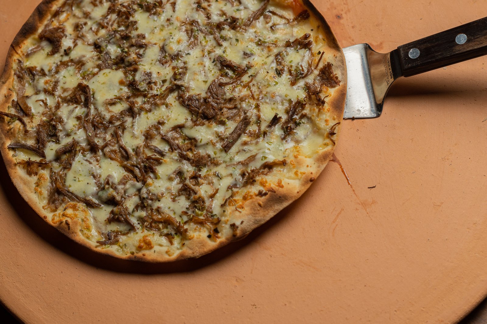 Pizza de carne desfiada sobre pedra da Pizza Da Hora